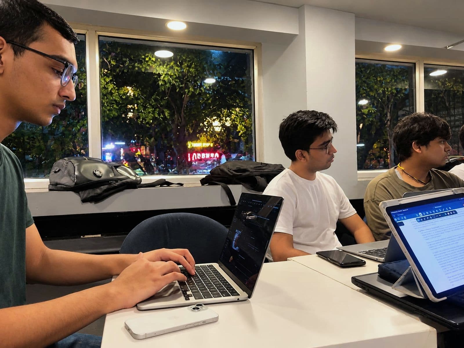 A participant typing notes by the window while two others read